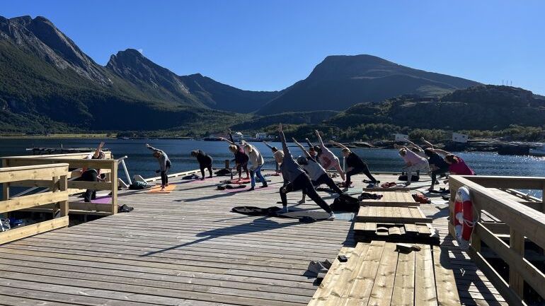 Mennesker gjør yoga på brygge