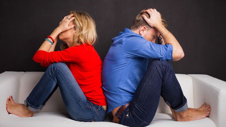Kvinne og mann i sofa med hodet i hendene